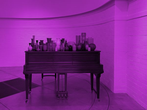 Photograph of piano topped with various ceramic objects, with purple overlay over image