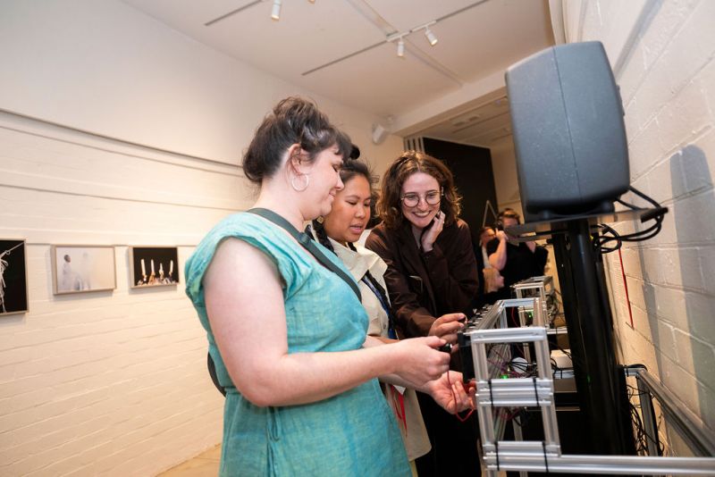 three people turn knobs on an interactive museum display