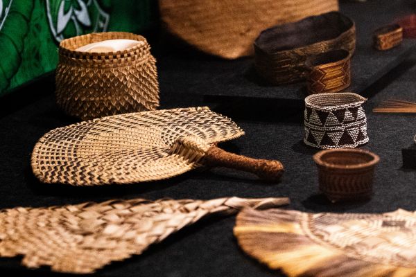 Weaving pasefika - woven items on display woven Pasefika items including a fan, laid out in a museum display case