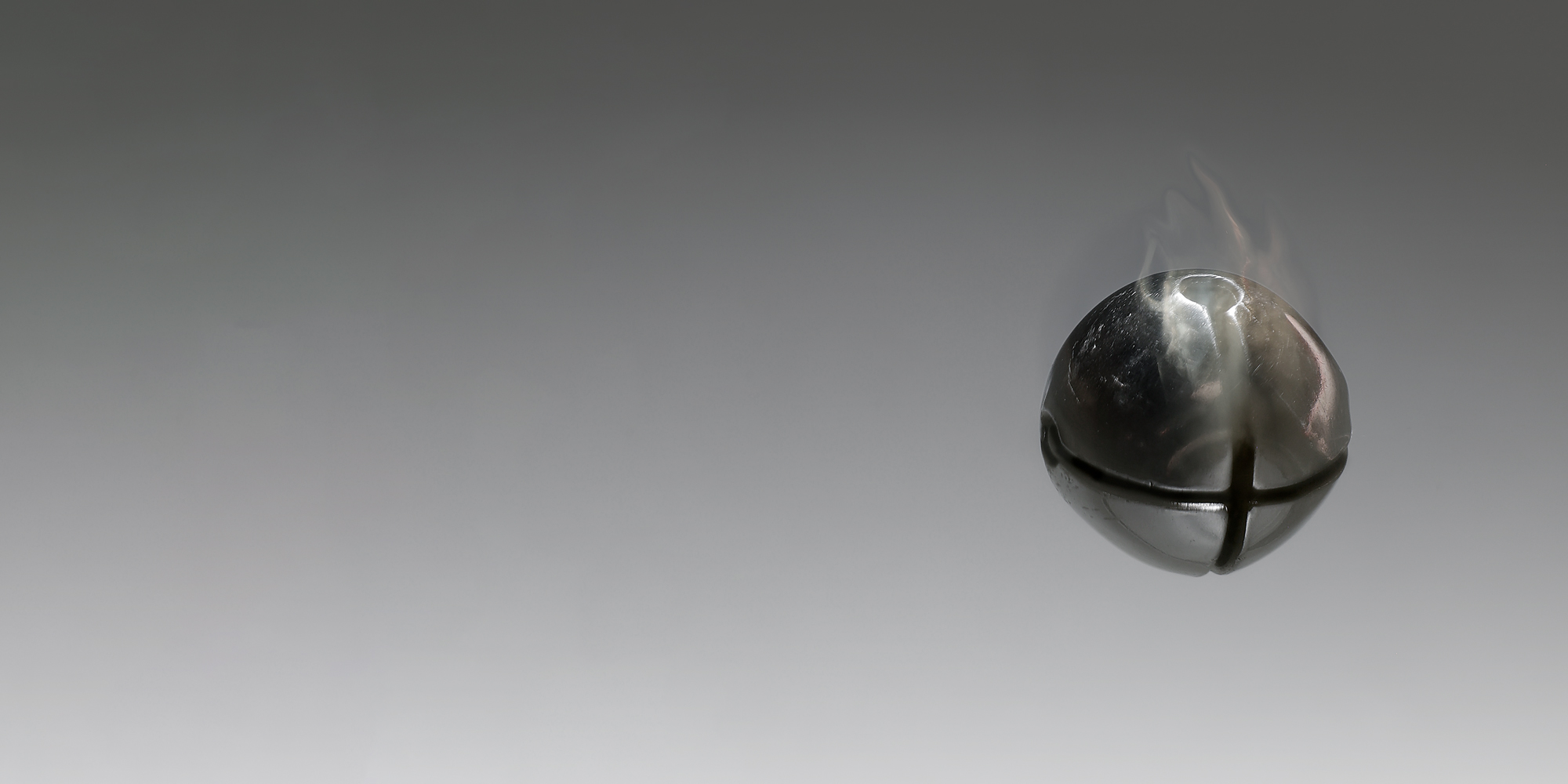 A silver bell against a grey background