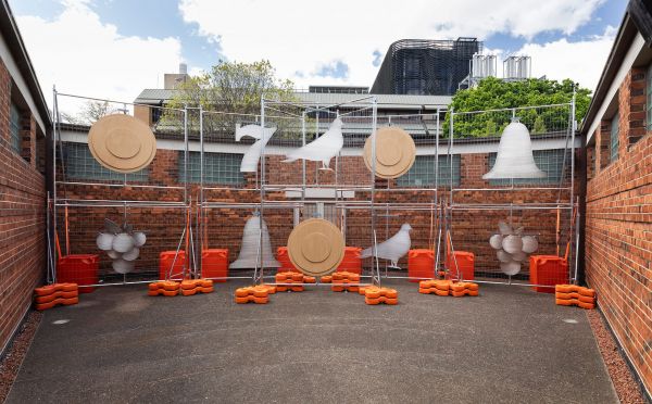 an art work suspended from scaffolding in a courtyard
